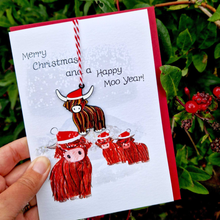 Load image into Gallery viewer, Christmas card with cartoon cows in Santa hats and text 'Merry Christmas and a Happy Moo Year!' held against a natural background.