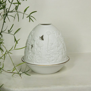 white candle holder with thistle engraved design and butterfly flying towards the thistle