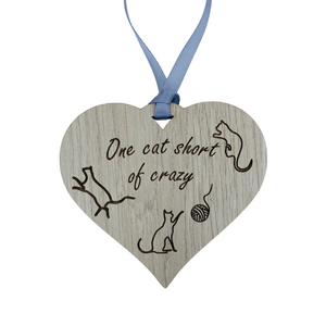 A hanging heart plaque featuring the phrase "One Cat Short of Crazy"