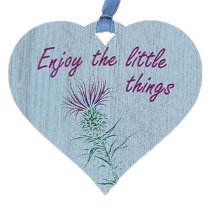 A hanging heart plaque featuring the phrase "Enjoy the Little Things"