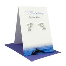 Load image into Gallery viewer, Sterling silver dolphin earrings on a card with a dolphin illustration.
